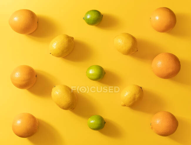 Vista dall'alto di vari agrumi freschi su sfondo giallo colorato — Foto stock