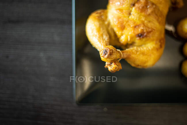 Vista superior da deliciosa galinha frita colocada na chapa preta sobre a mesa de madeira escura no restaurante — Fotografia de Stock