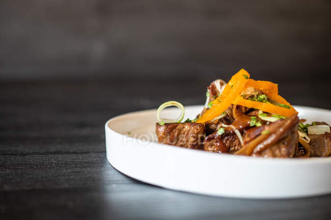 Carne fritta deliziosa servita con salsa ed erbe su un piatto di ceramica su un tavolo di legno nero — Foto stock