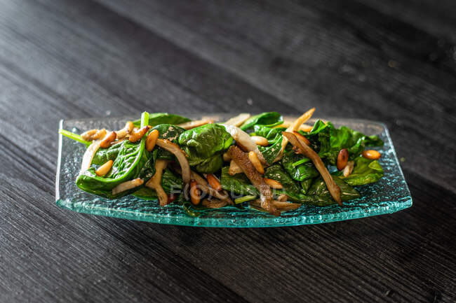 Da suddetto piatto di vetro d'insalata di spinaci saporita con funghi messi su tavolo nero di legno in caffè — Foto stock