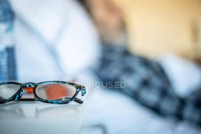 Primo piano di occhiali di paziente più anziano su tavolo bianco vicino a letto in reparto di ospedale — Foto stock