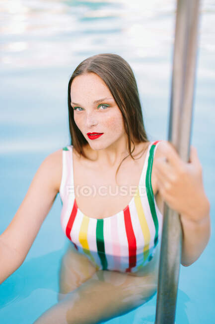 Close-up of a brunette girl with long hair on a stairs in the pool — Stock Photo