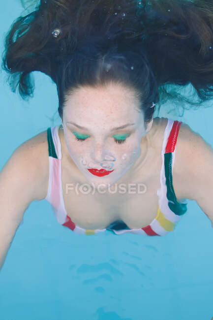 Primo piano di una ragazza bruna con i capelli immersi in piscina con gli occhi chiusi — Foto stock