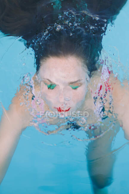 Close-up de uma menina morena com cabelos longos em uma escada na piscina — Fotografia de Stock