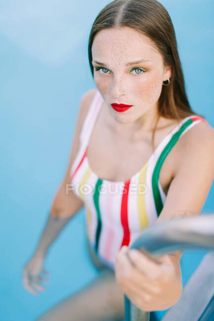 Primo piano di una ragazza bruna con i capelli lunghi su una scala in piscina — Foto stock