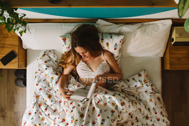 Зверху самки лягають у зручне ліжко і читають книжку вранці. — стокове фото