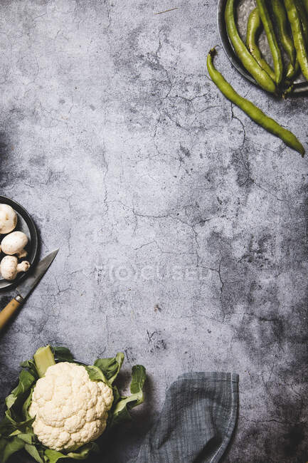 Vue de dessus des gousses vertes organiques sur plateau rond en métal avec champignons et chou-fleur sur la surface grunge gris — Photo de stock