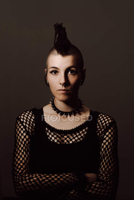 Serious adult lady with mohawk looking at camera while standing against brown background — Stock Photo