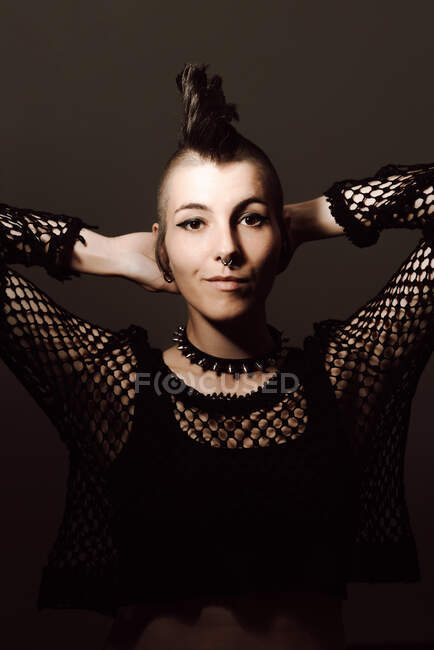 Adult lady with mohawk looking at camera while standing against brown background — Stock Photo