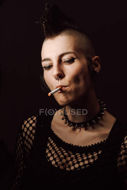 Erwachsenes Weibchen mit Mohawk und Piercing beim Zigarettenrauchen — Stockfoto