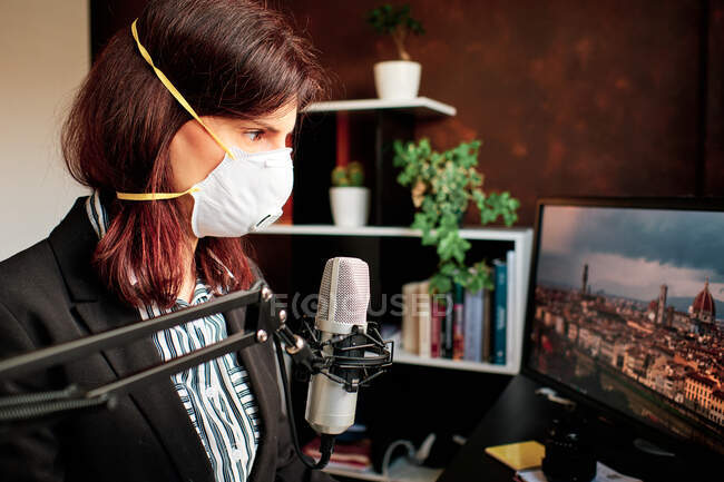 Femme avec masque travaillant à la maison et baladodiffusion avec un microphone — Photo de stock