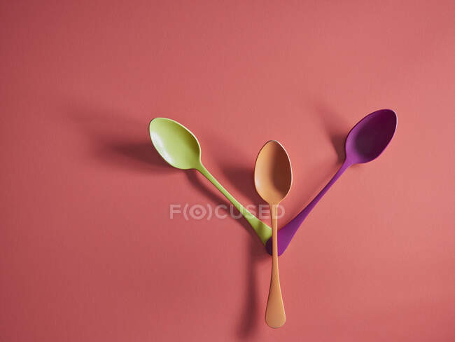 Colorful spoons on red paper background — Stock Photo