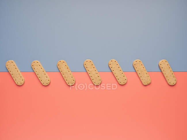 Crispy cookies on gray and coral paper sheets — Stock Photo