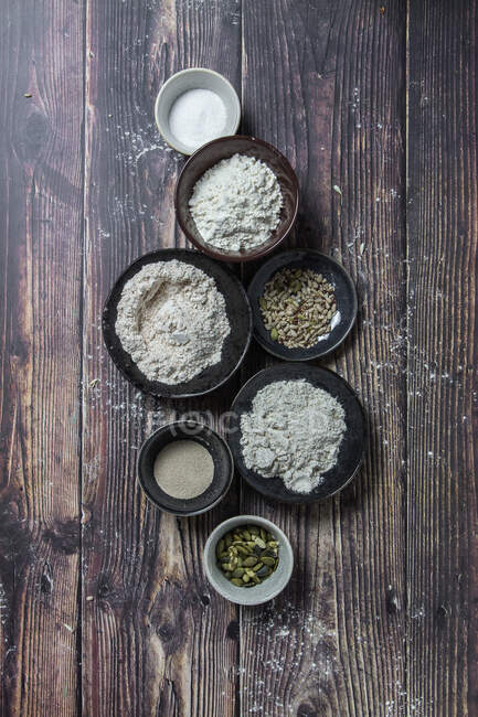 Posa piatta di tipi assortiti di farina di pane e additivi su superficie di legno rustica con grano — Foto stock