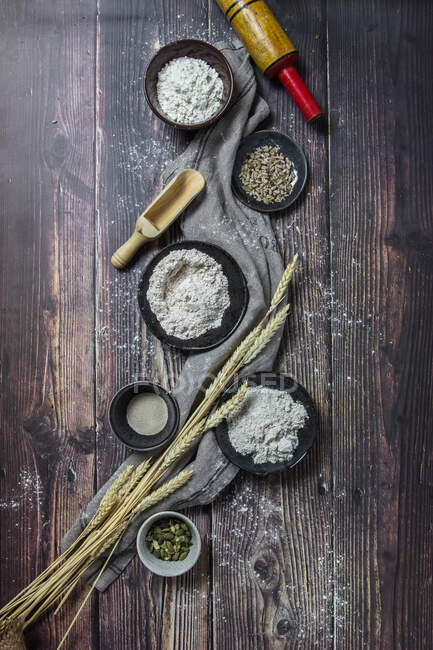 Pose plate de divers types de farine de pain et d'additifs sur une surface en bois rustique avec du blé — Photo de stock