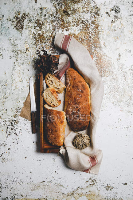De composition rustique avec des pains aromatiques à bord avec serviette en lin et couteau sur une surface minable — Photo de stock