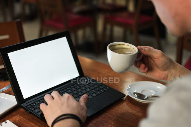 Freelancer sitting at cafe table and browsing laptop — Stock Photo