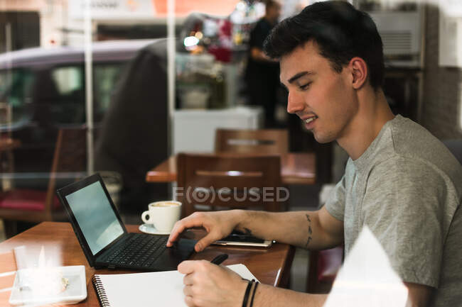 Freelancer sentado na mesa de café e laptop de navegação — Fotografia de Stock