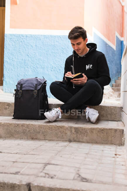 Студент-мужчина делает заметки на улице — стоковое фото