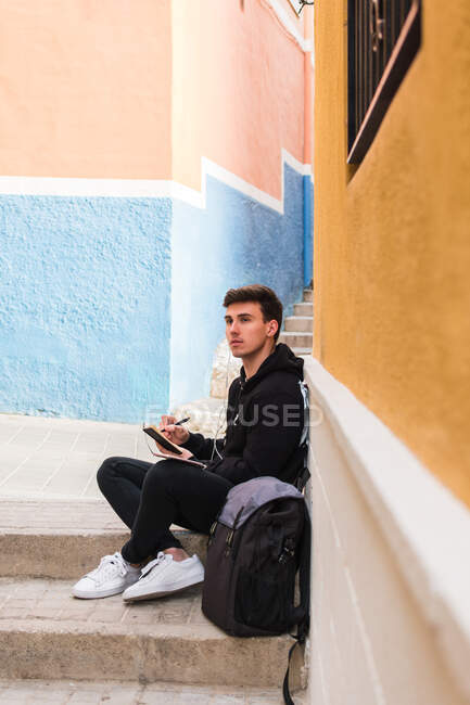 Estudiante masculino haciendo notas en la calle - foto de stock