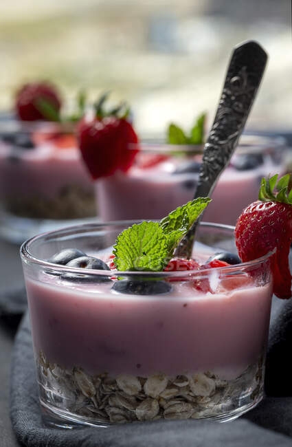 Yogurt fatto in casa con fragole, mirtilli e cereali con sfondo scuro e luce del sole.Cibo sano. — Foto stock