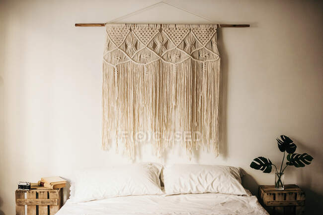Vintage macrame decoração pendurada na parede sobre cama confortável no quarto aconchegante em casa — Fotografia de Stock
