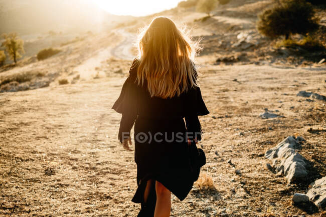 Stylish woman standing on rock in countryside — Stock Photo