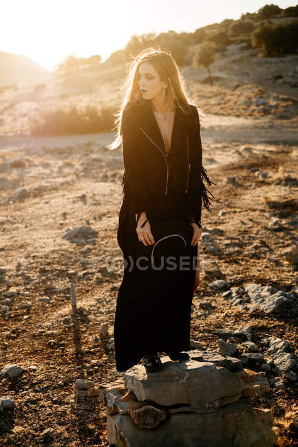 Stylish woman standing on rock in countryside — Stock Photo