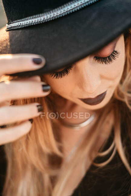 Trendy lady touching hat and looking down — Stock Photo