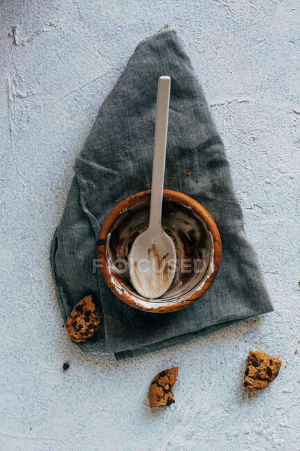 From above pieces of yummy oatmeal cookies placed on plaster surface near cloth napkin and empty bowl with stains of ice cream and spoon — Stock Photo