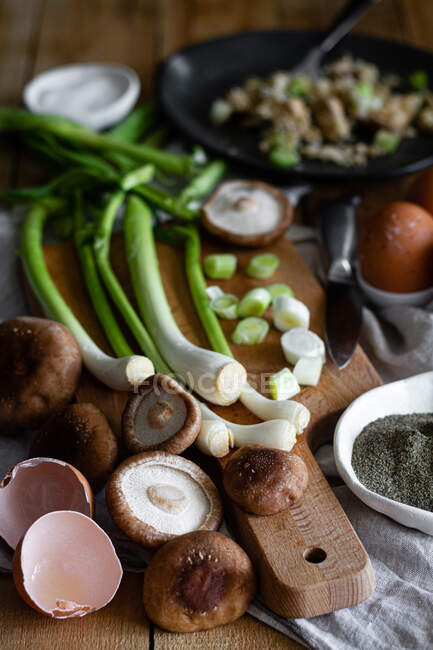 De cima cebolinha madura e cogumelos colocados perto de cascas de ovo e sementes de papoula na mesa na cozinha rústica — Fotografia de Stock