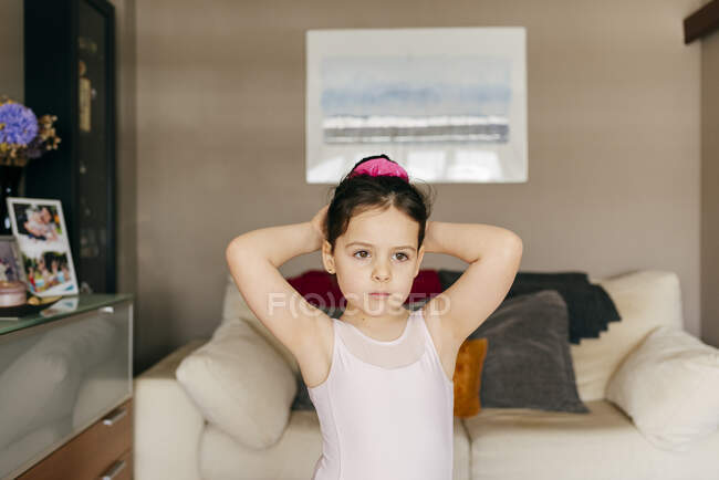Adorabile ragazza ballerina sconvolta in body guardando lontano mentre faceva hair bun prima della formazione di balletto in accogliente soggiorno a casa — Foto stock