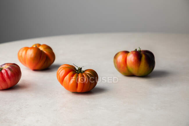 Сверху аппетитные красные органические помидоры, приготовленные для приготовления пищи, размещены на круглом столе на кухне — стоковое фото