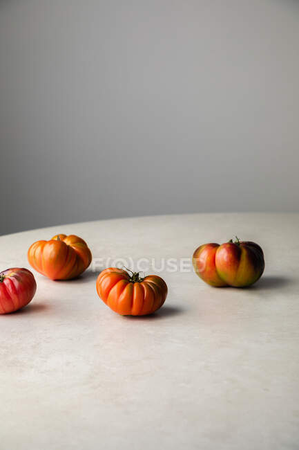 Ripening tomatoes on white table — Stock Photo