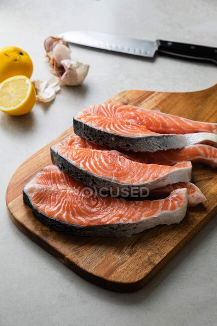 Fresh fish steaks on wooden board — Stock Photo