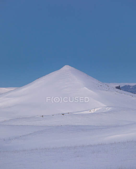 Paysage hivernal avec colline enneigée et vallée sous un ciel bleu clair — Photo de stock