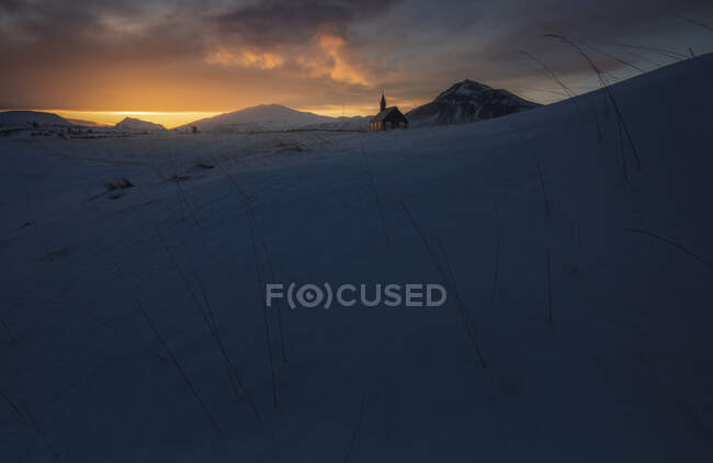 Lonely church against sunset sky in snowy valley — Stock Photo