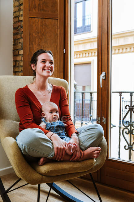 Mãe com bebê sentado perto da janela — Fotografia de Stock