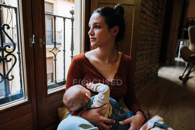 Glückliche Mutter stillt Baby am Fenster — Stockfoto
