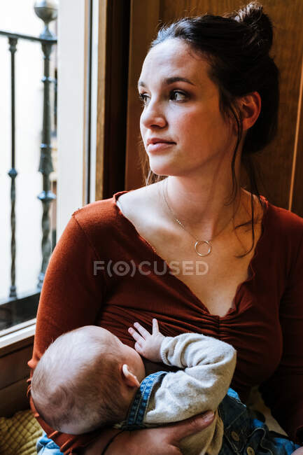 Glückliche Mutter stillt Baby am Fenster — Stockfoto