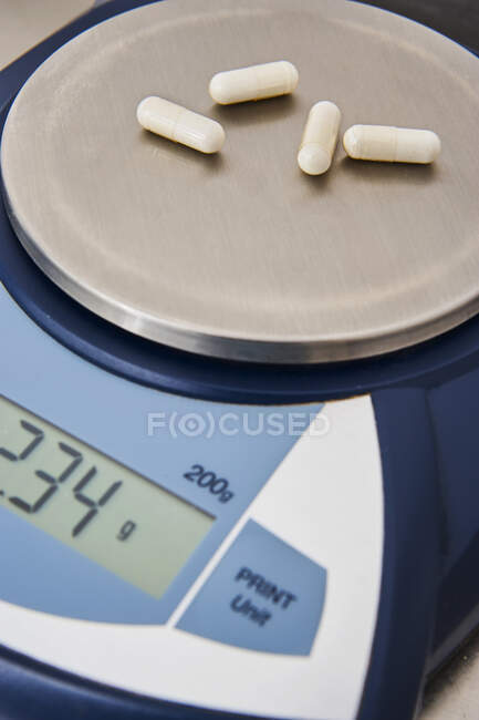 Pesaje de cápsulas y pastillas en escalas precisas de medicamentos y productos farmacéuticos líquidos en laboratorio. - foto de stock