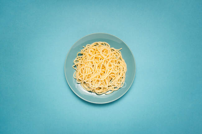 From above of blue ceramic plate with homemade cooked pasta on bright blue background — Stock Photo