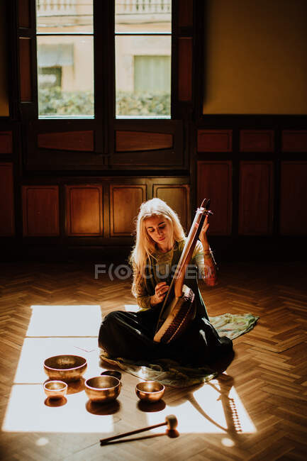 Donna che suona la lira vicino alle ciotole tibetane — Foto stock