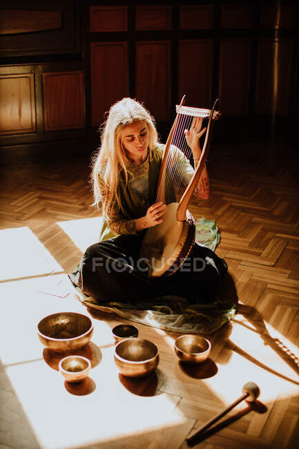 Frau spielt Leier in der Nähe tibetischer Schalen — Stockfoto