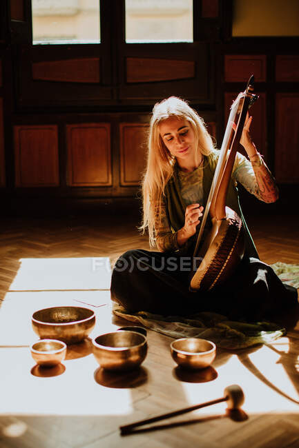 Femme jouant de la lyre près des bols tibétains — Photo de stock