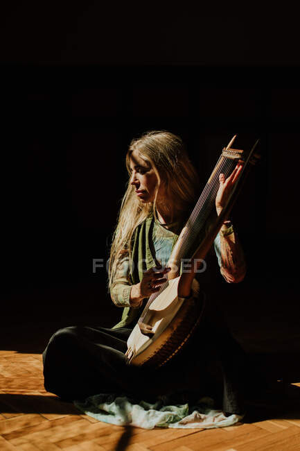 Mulher tocando lira no quarto escuro — Fotografia de Stock