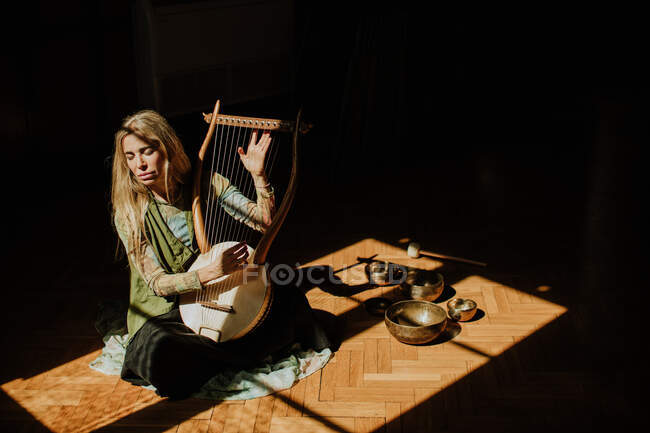 Femme jouant lyre dans chambre noire — Photo de stock