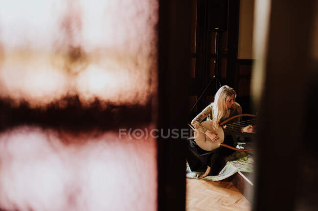 Femme jouant lyre à la maison — Photo de stock