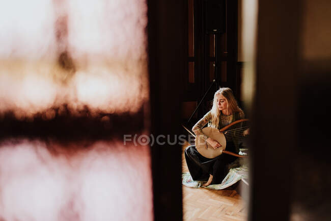 Woman playing lyre at home — Stock Photo