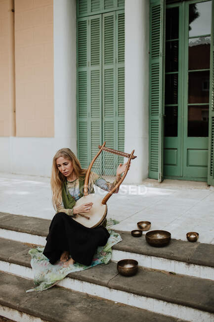 Woman playing lyre on steps — Stock Photo
